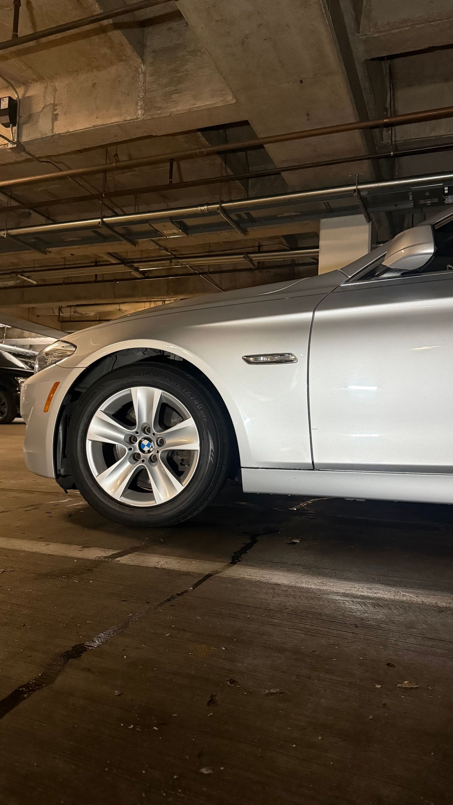 Silver sedan parked in a dim underground garage, side view