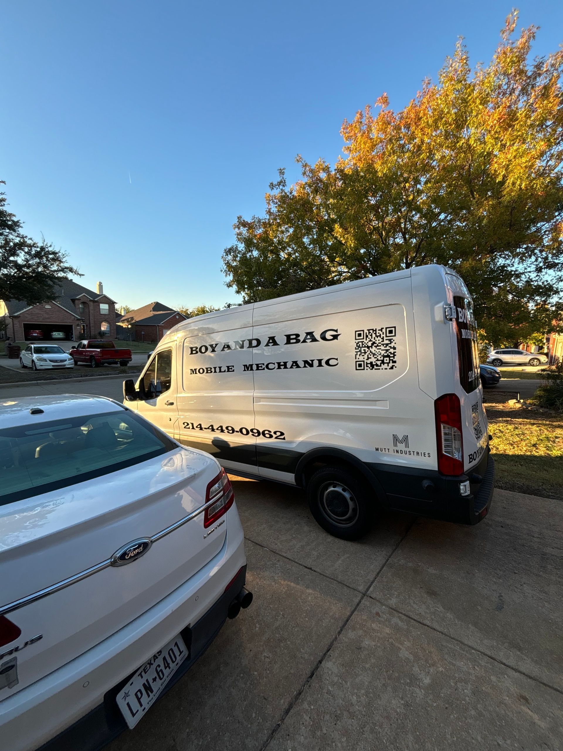 White service van with company logo parked on a street beside other cars under autumn trees at sunset