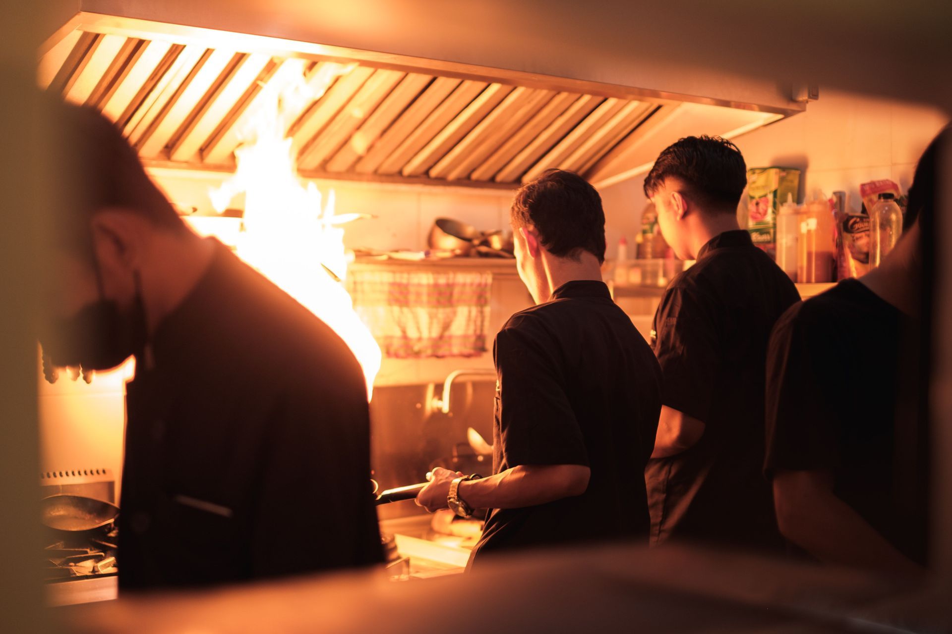 Mensen staan aan een aanrecht in een sfeervol verlichte keuken, van achteren gezien.