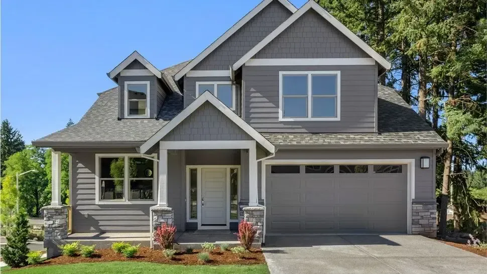 Gray two-story suburban house with attached garage, white trim, and a small front porch under a clear blue sky