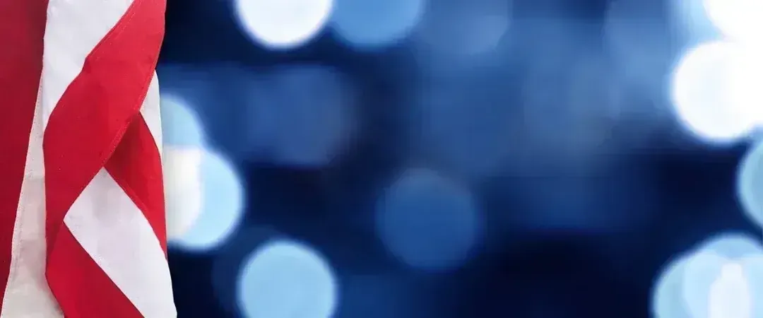 Close-up of a red-and-white flag against a blue background with soft bokeh lights