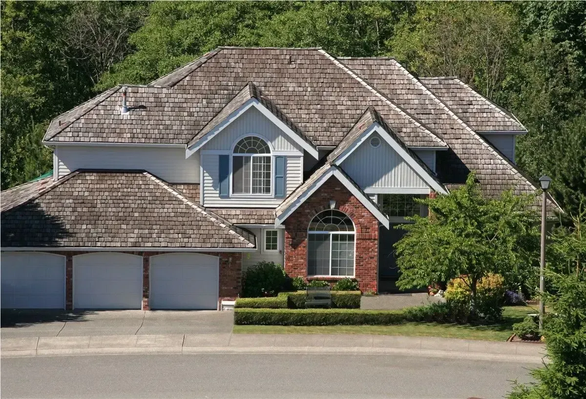 Large suburban house with a shingled roof, two-car garage, and landscaped front yard.