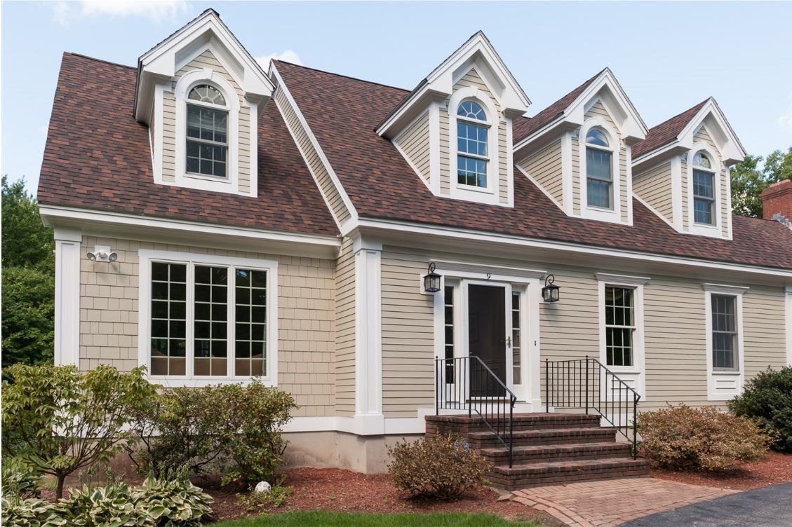 Suburban house with beige siding, red shingle roof, white trim, and front porch