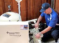a man in a blue shirt and hat is working on a pool pump .