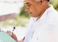 a man is writing on a clipboard with a pen .