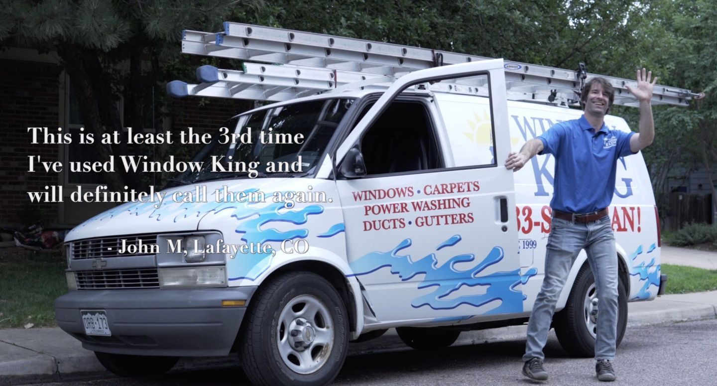 Man standing beside a white van with a ladder, both covered in painted graffiti-style text and drawings.