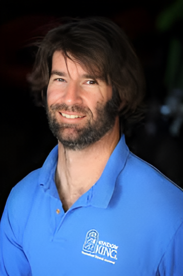 Smiling man in a blue polo shirt against a dark background