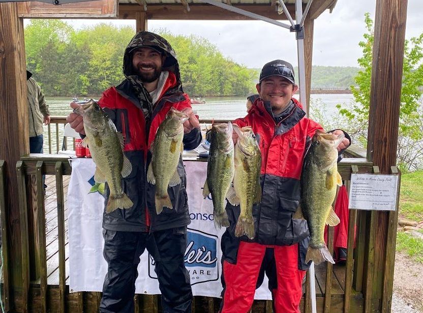Two men participating in Orange Grove's Fishing Tournament, holding up five largemouth bass fish.