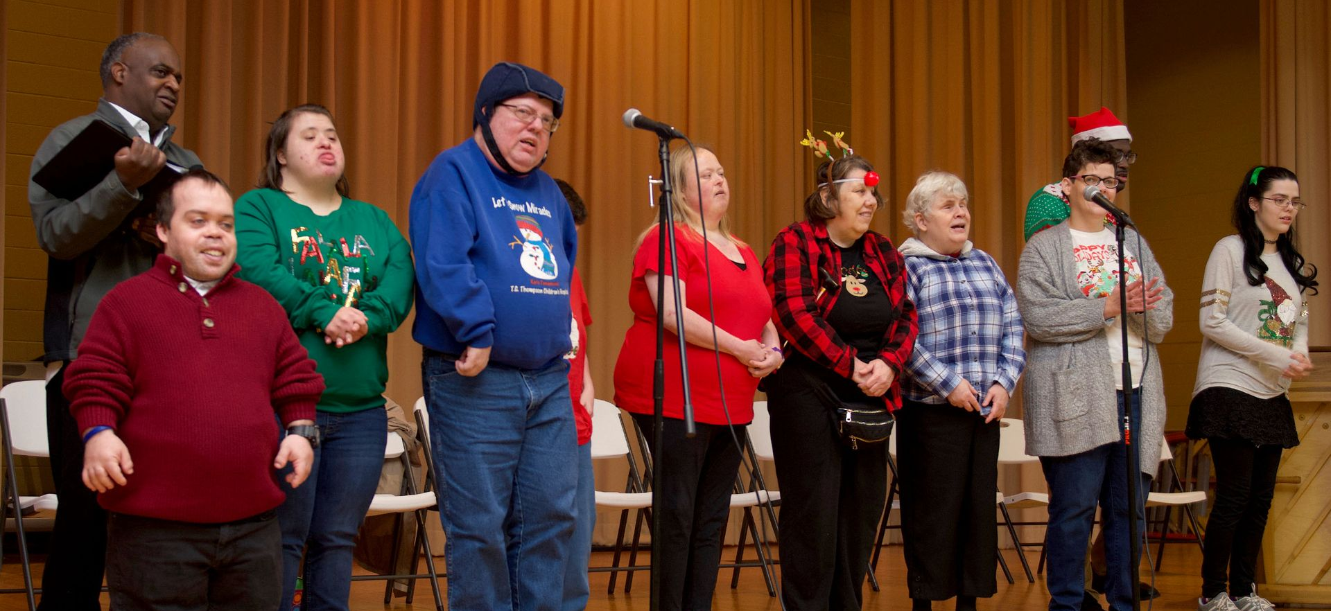 A group of singers standing on a stage and singing during a choral Christmas performance.