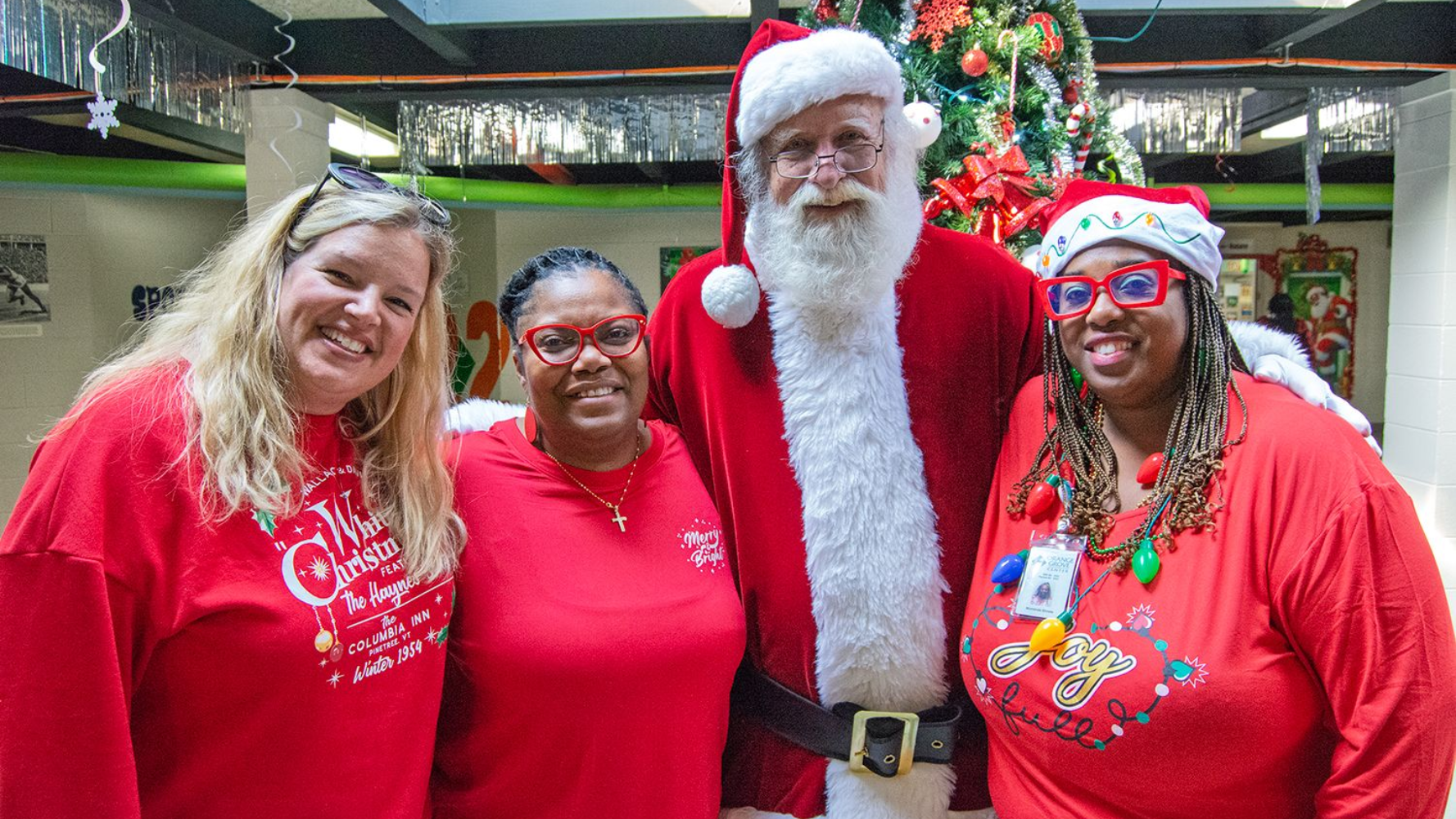Three female employees of Orange Grove pose for a group photo with a volunteer dressed as Santa Claus.