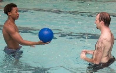 two men in a pool with a ball