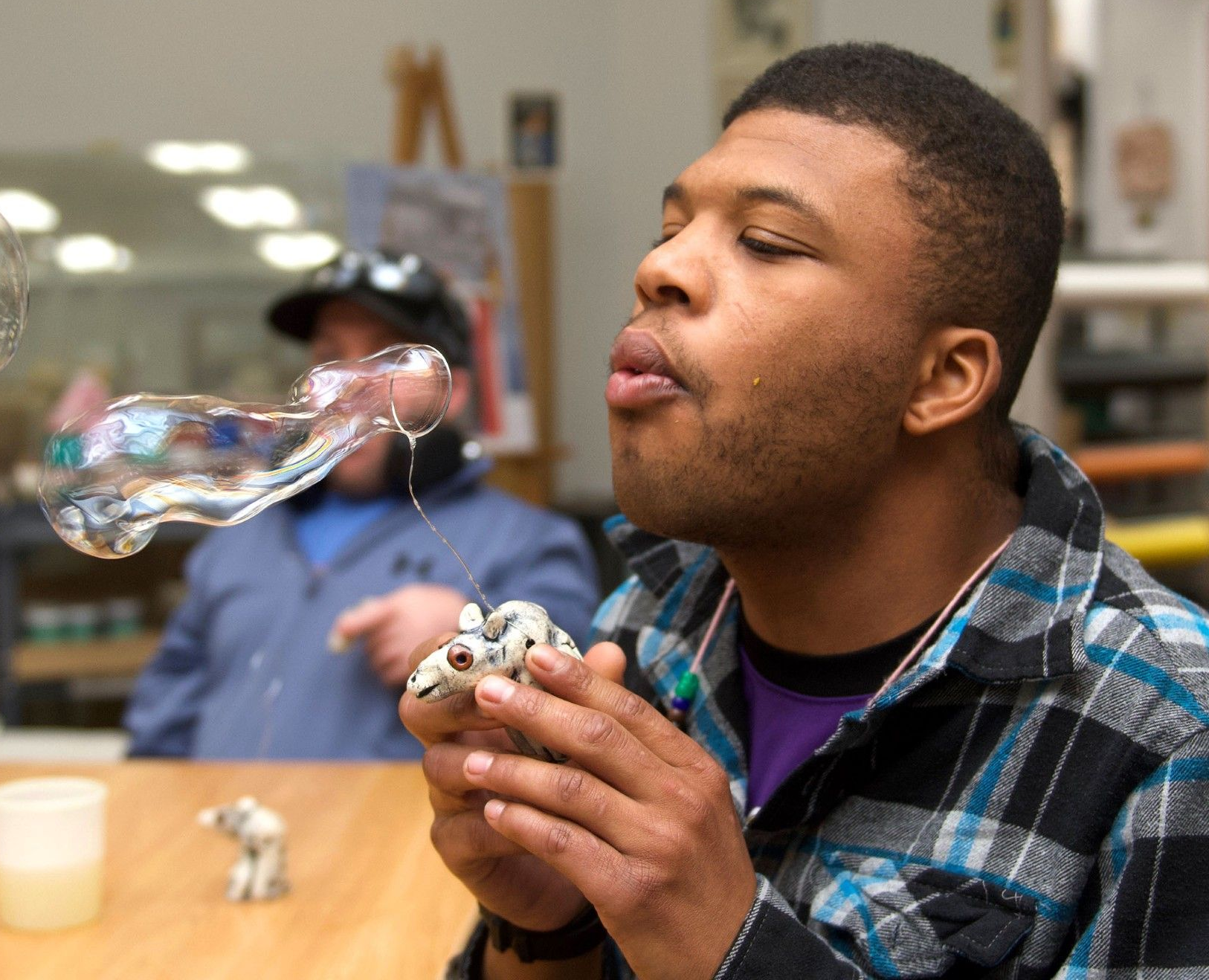 A young man blows bubbles out of a sculpture he's created in Orange Grove Center's art class.