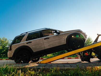 Off-road SUV on a tilted tow ramp under a blue sky