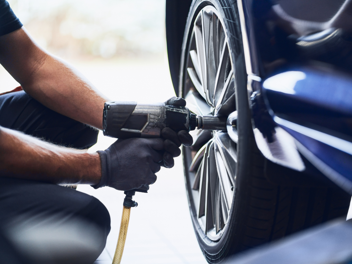 Mechanic using an impact wrench to change a car wheel lug nut