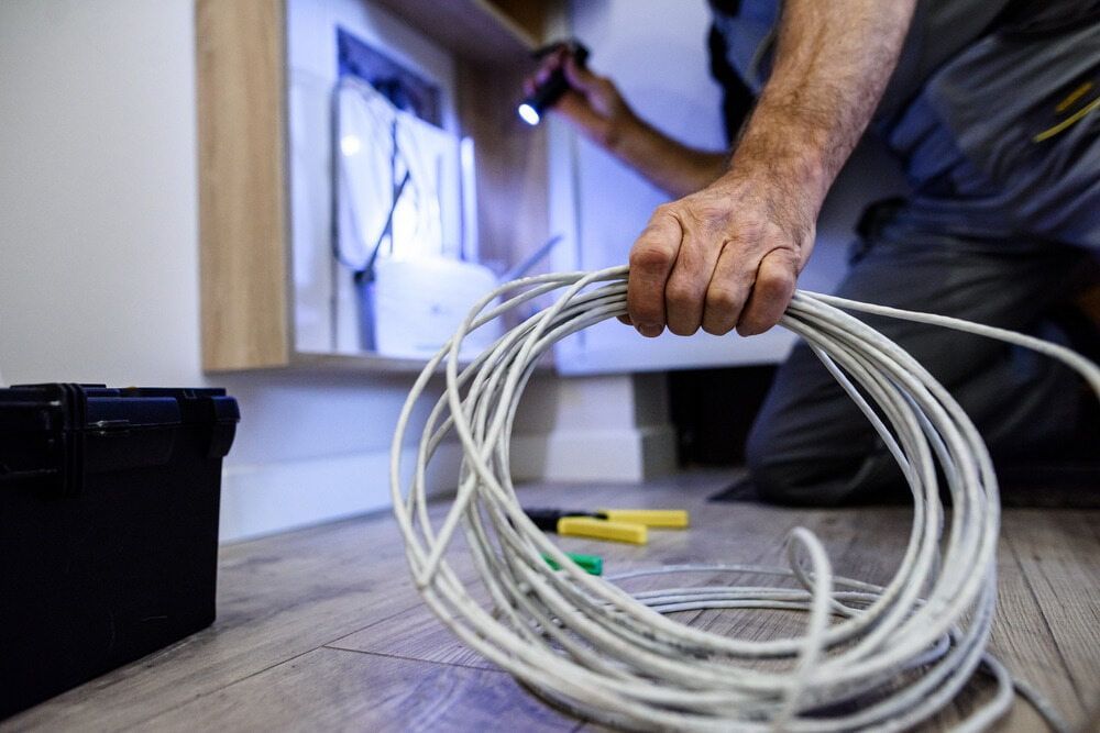 A Man is Holding a Roll of Wire in His Hands — J.A.F. Electrical Solutions in Kawana, QLD