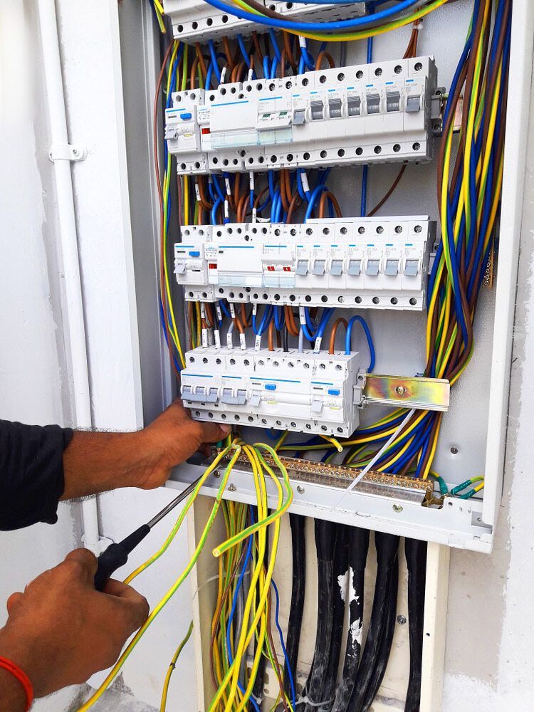 A Man is Working on an Electrical Box With a Screwdriver — J.A.F. Electrical Solutions in Kawana, QLD