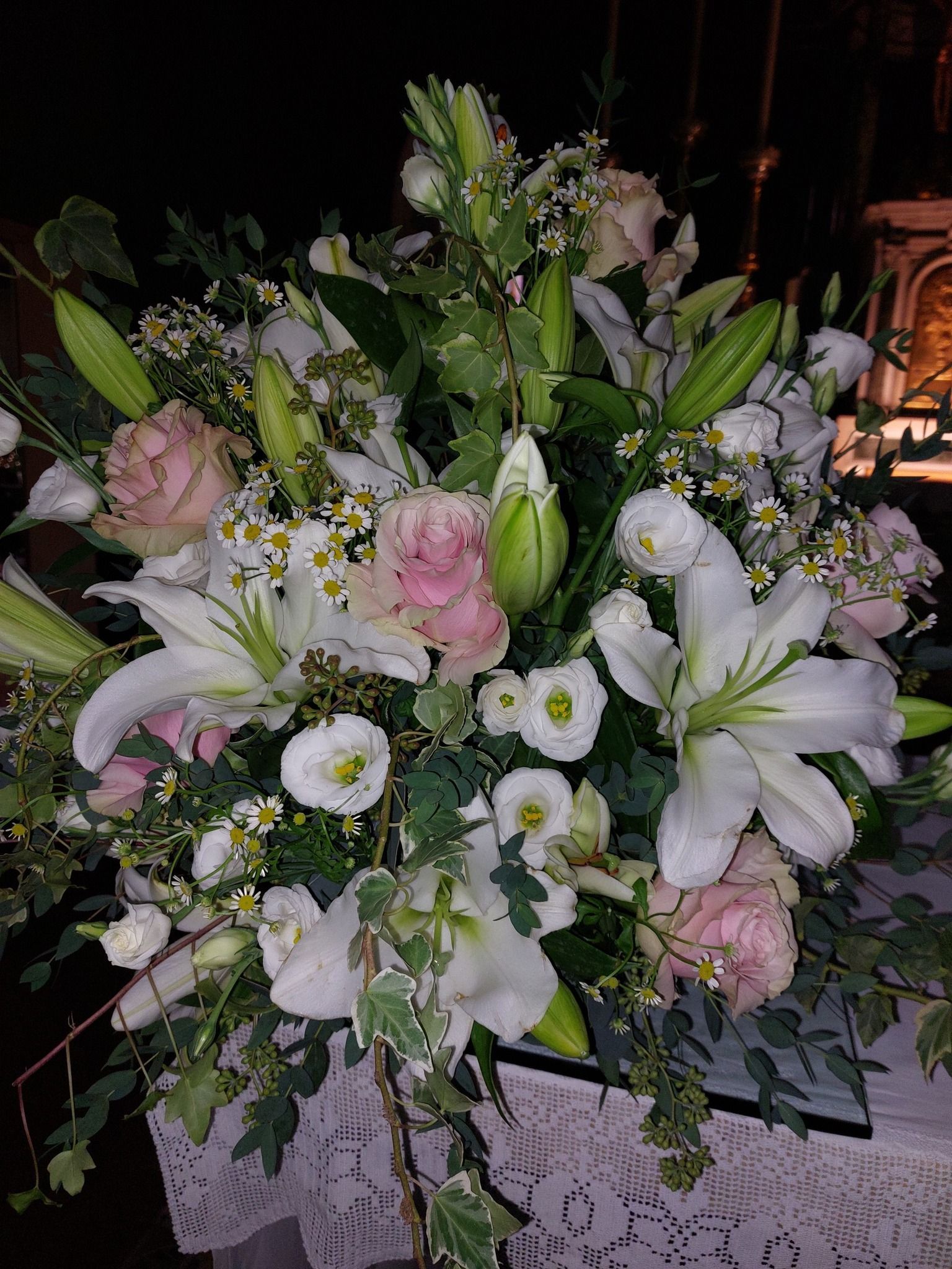 Bouquet di gigli bianchi e rose rosa con verde, su un tavolo.