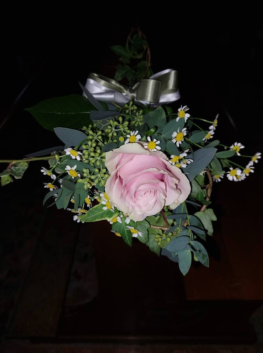 Bouquet di rose rosa e verde con un nastro argentato, su uno sfondo scuro.