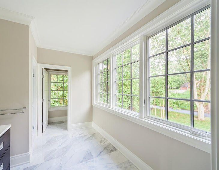 Bright white hallway with large windows, marble floor, and a view of green trees outside