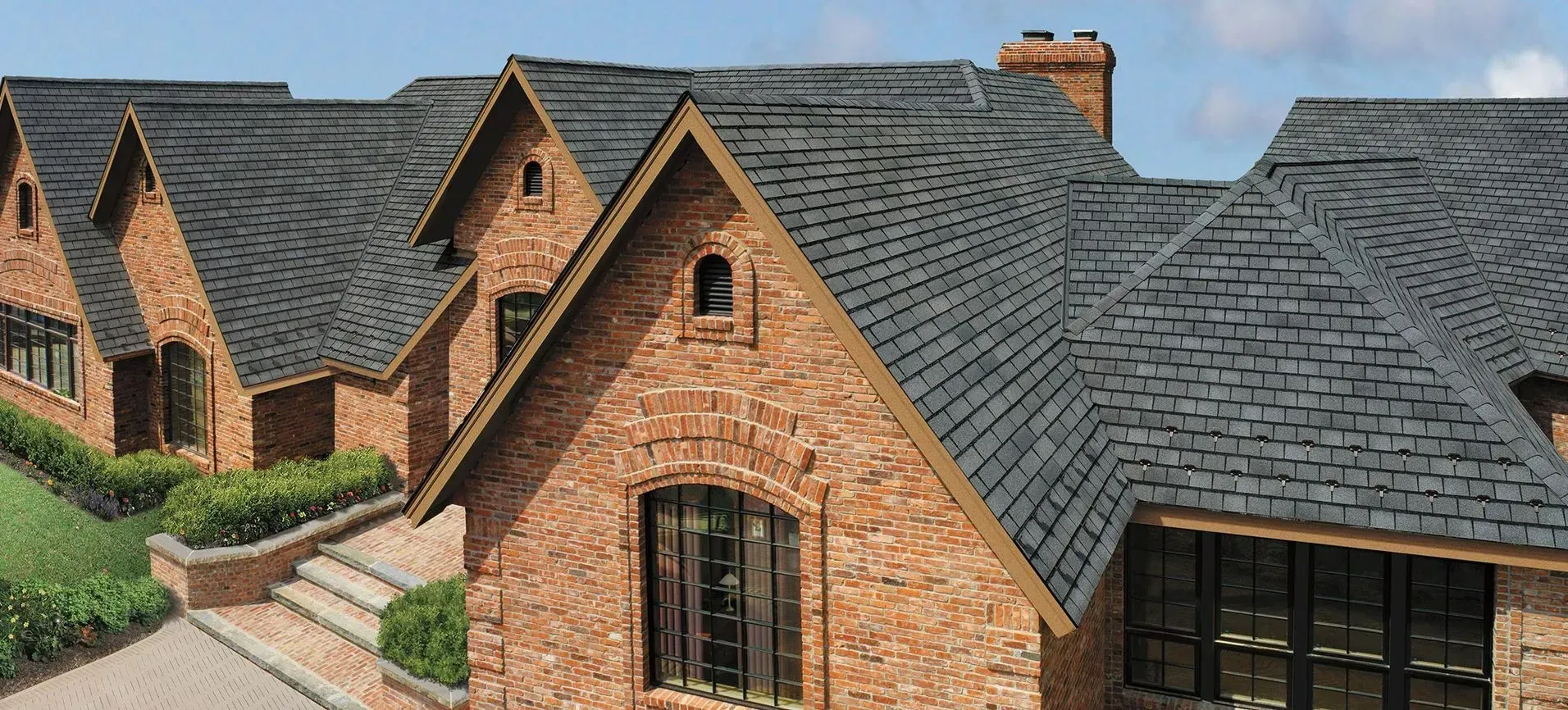 Brick houses with steep gray roofs and arched windows in a landscaped residential complex