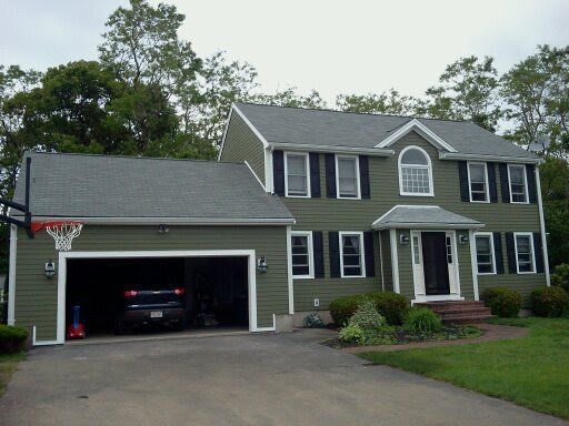 Two-story gray house with white trim, attached garage, and a basketball hoop in the driveway