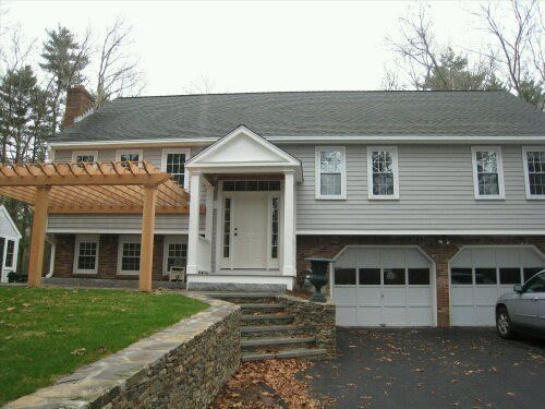 Gray two-story house with a front porch, pergola, and attached garage on a driveway