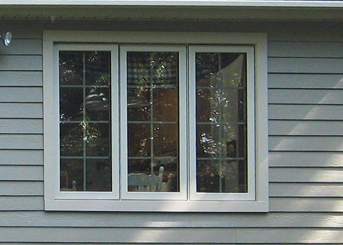 Three-pane window with white frame and grids on a light blue siding exterior wall. Energy Efficient | MasterCraft Roofing, Siding & Windows | Serving Eastern MA, NH & Selected Areas of VT