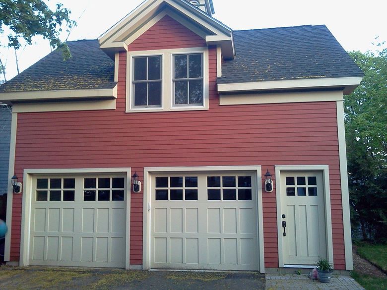 Red two-story house with white trim, two garage doors, and a side entry door