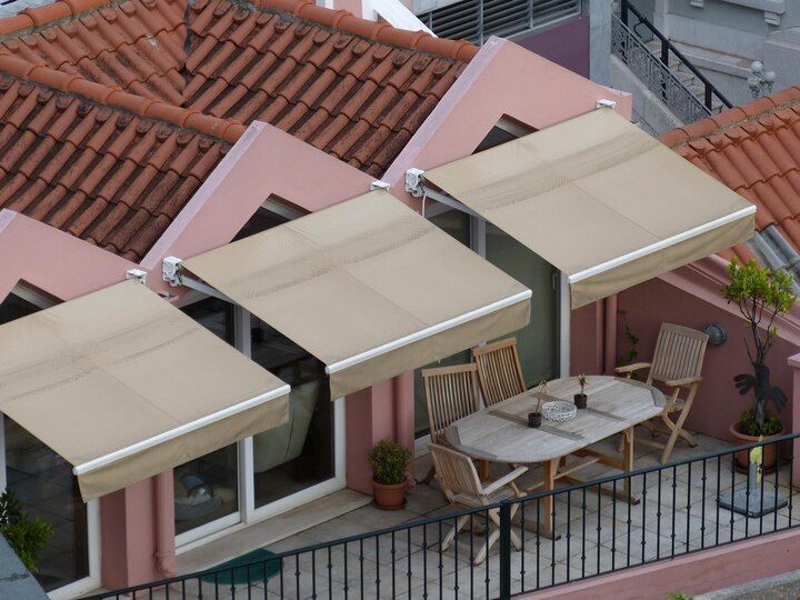 Balconies with beige awnings and a patio table beneath red-tiled roofs