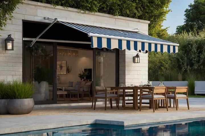 Modern patio with blue-striped awning, dining table, and pool beside a small stone house