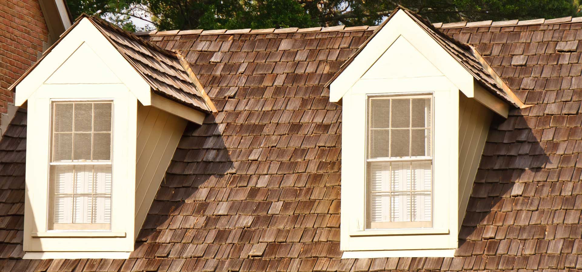 Two white dormer windows on a brown shingled roof