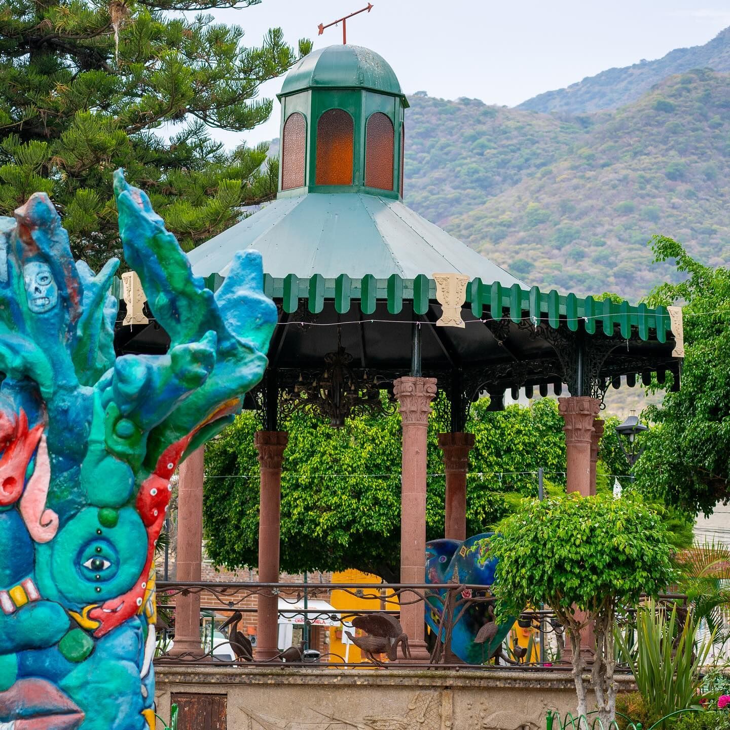 A gazebo with a green roof and a statue in front of it