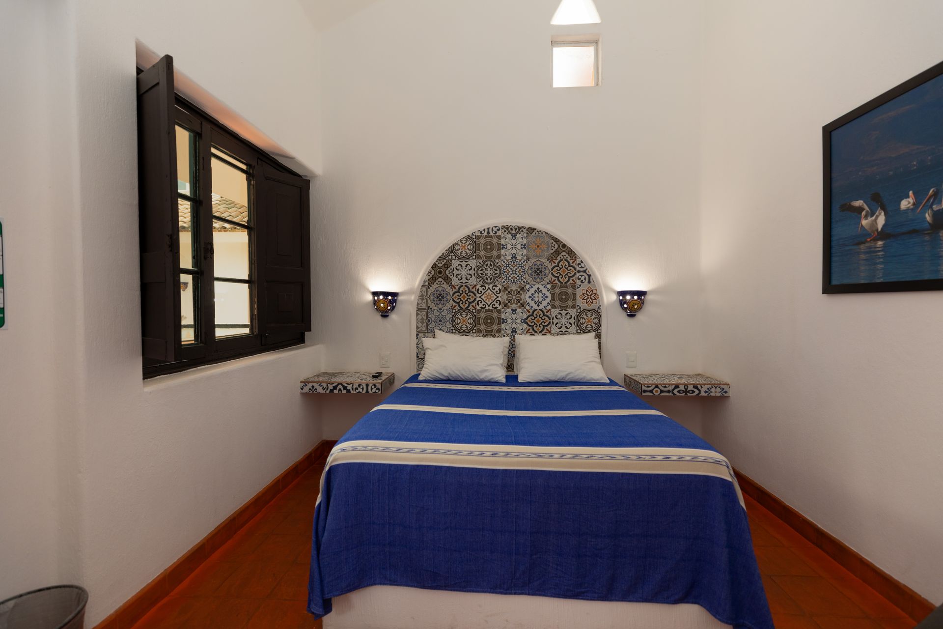 A bedroom with a blue bed and two windows