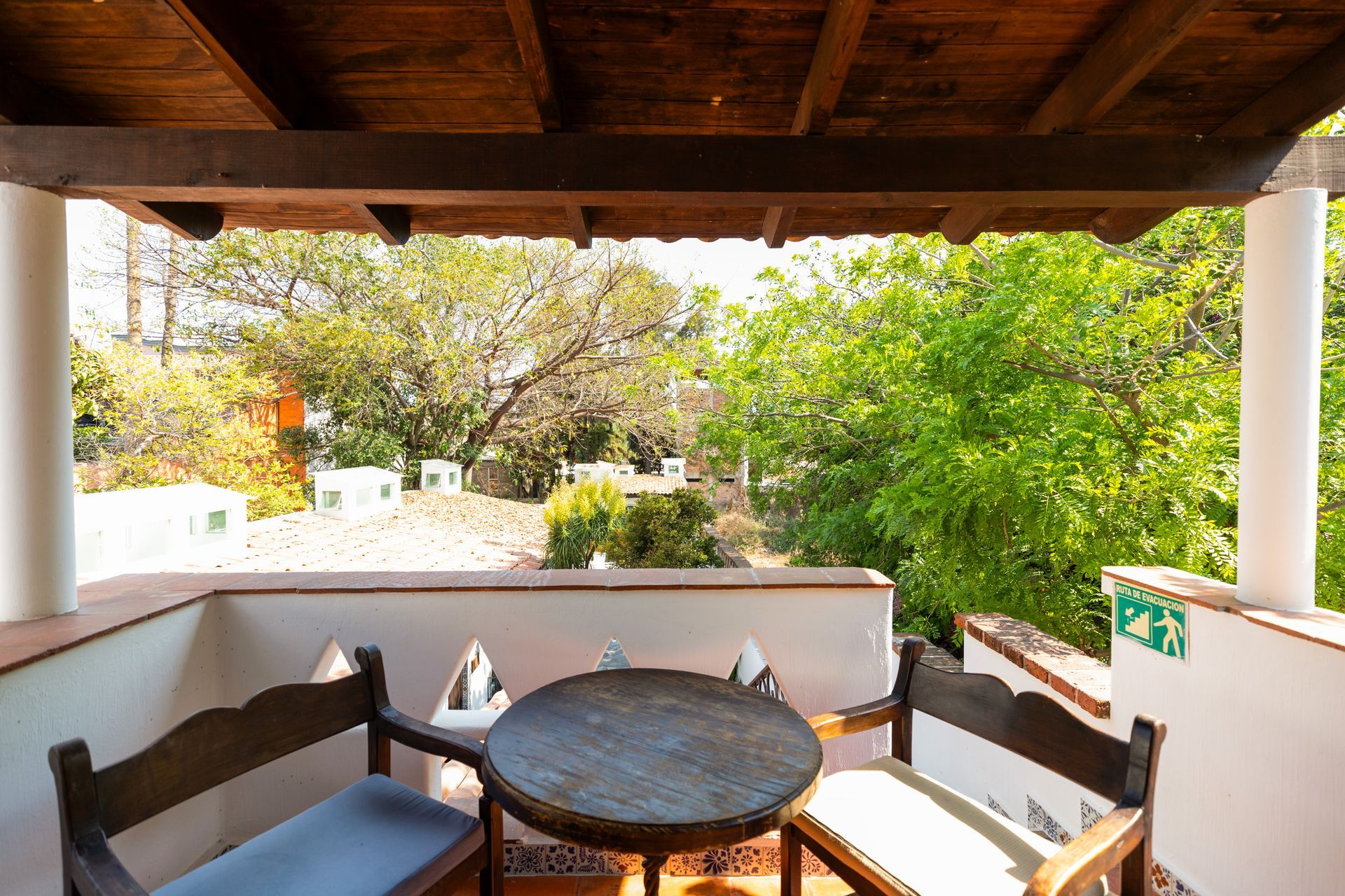 A balcony with a table and chairs and trees in the background