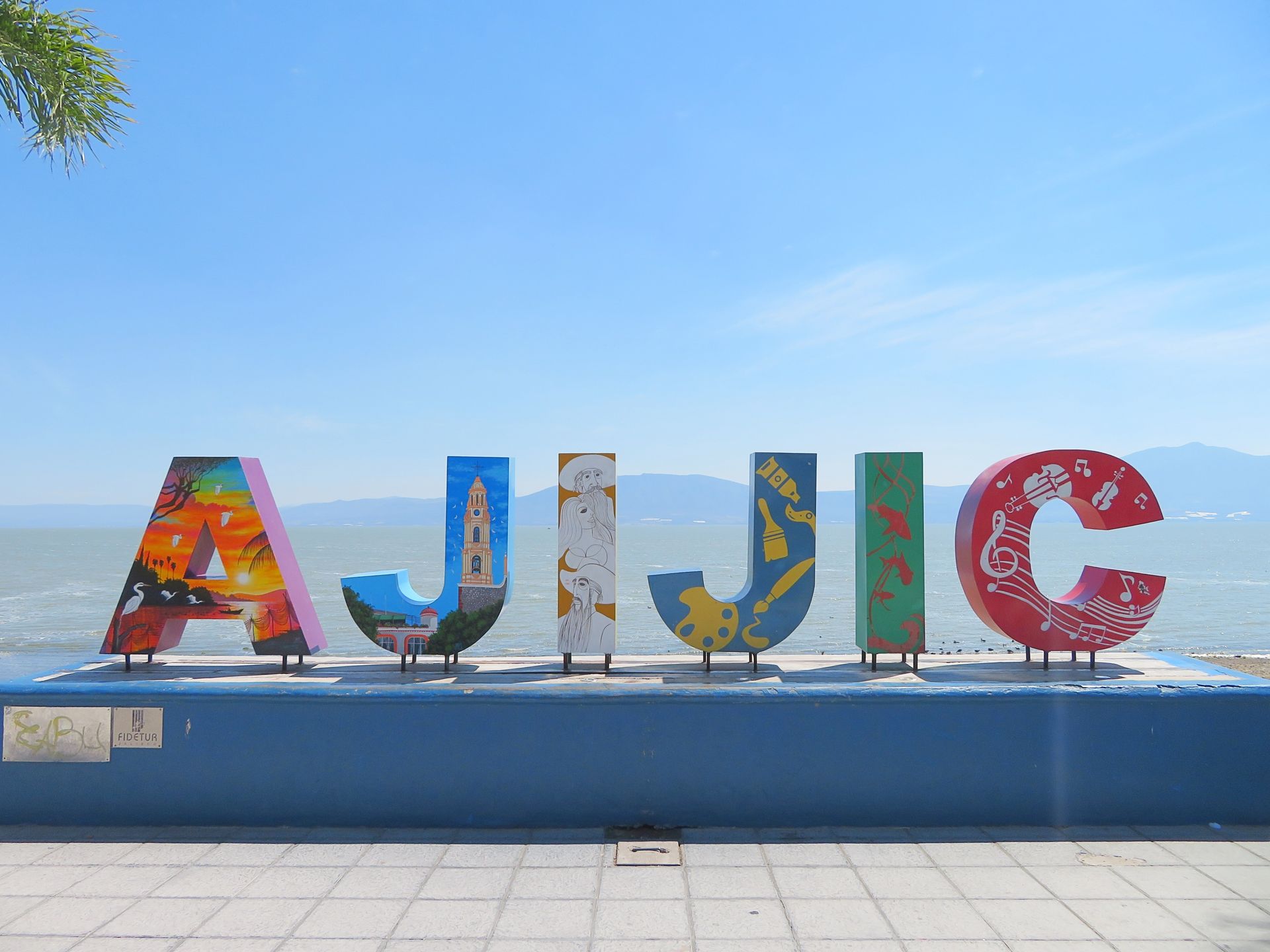 The word ajujic is written in colorful letters on a blue wall.