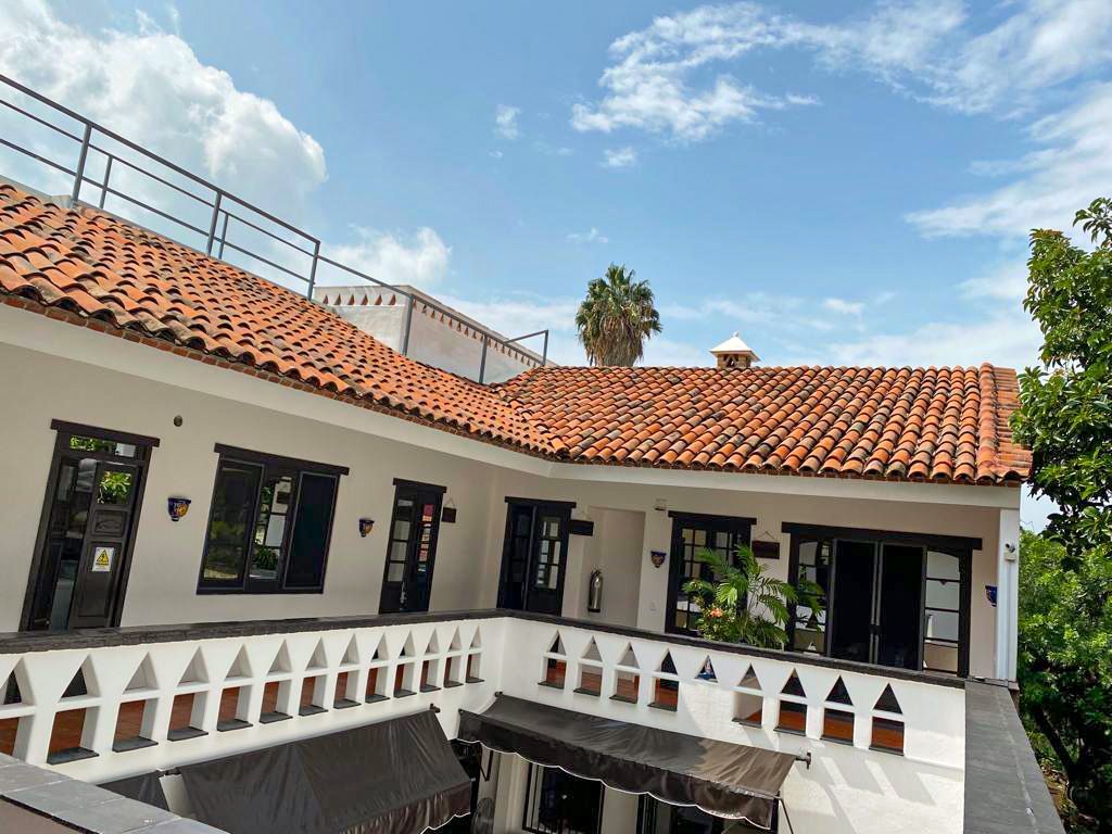 A white building with a red tile roof and a balcony.