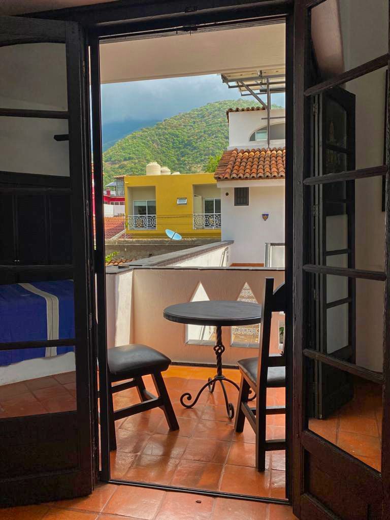 A balcony with a table and chairs and mountains in the background