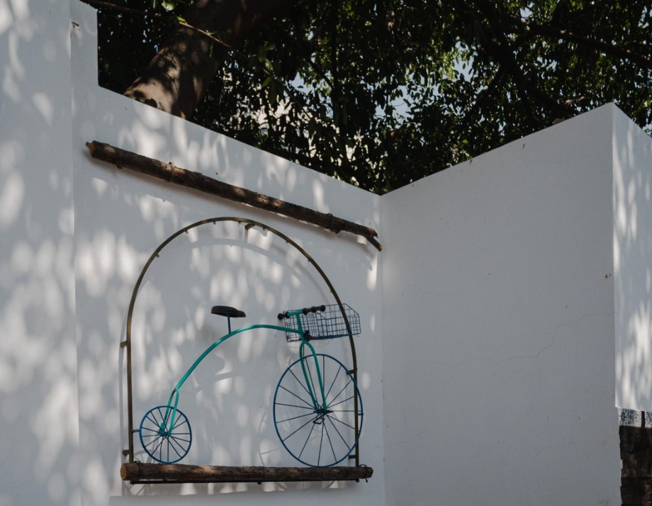 A bicycle with a basket is hanging on a white wall.