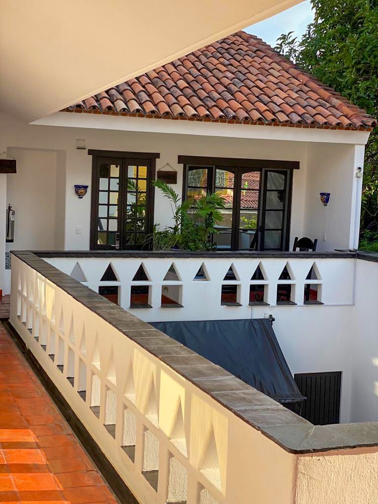 A white house with a red tile roof and a balcony