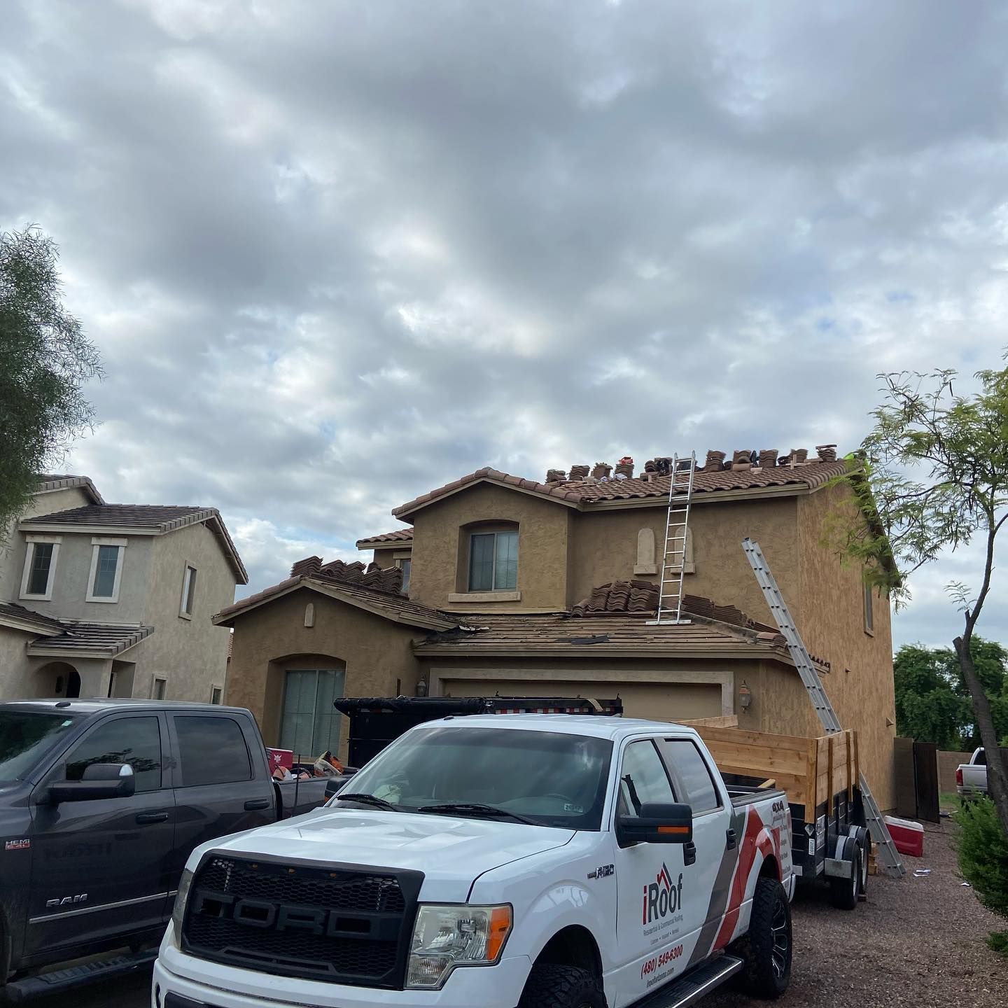 House with roofing work in progress, ladder, truck, and cloudy sky.