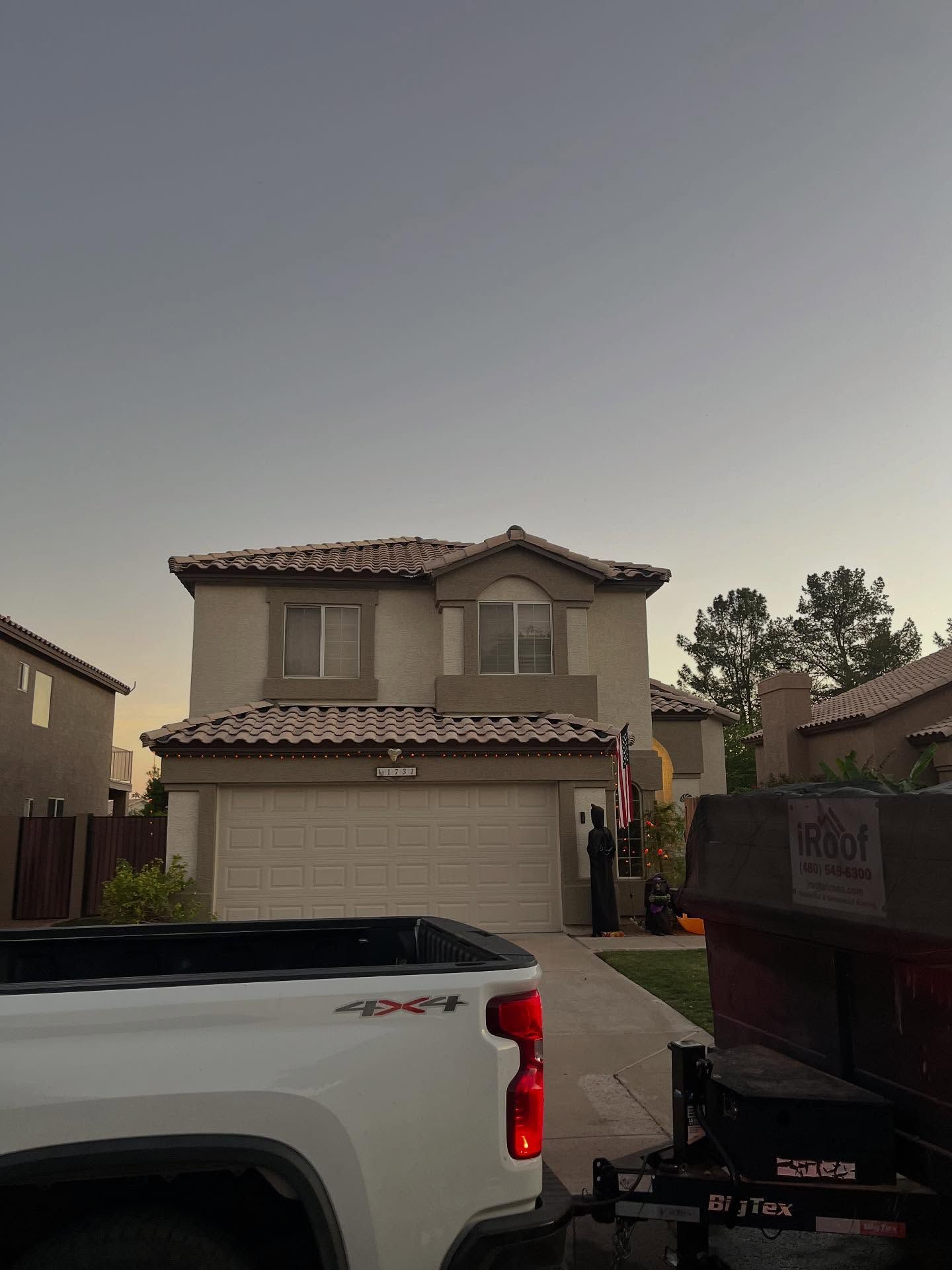 Two-story beige house with a truck parked in front. A dumpster is to the right.