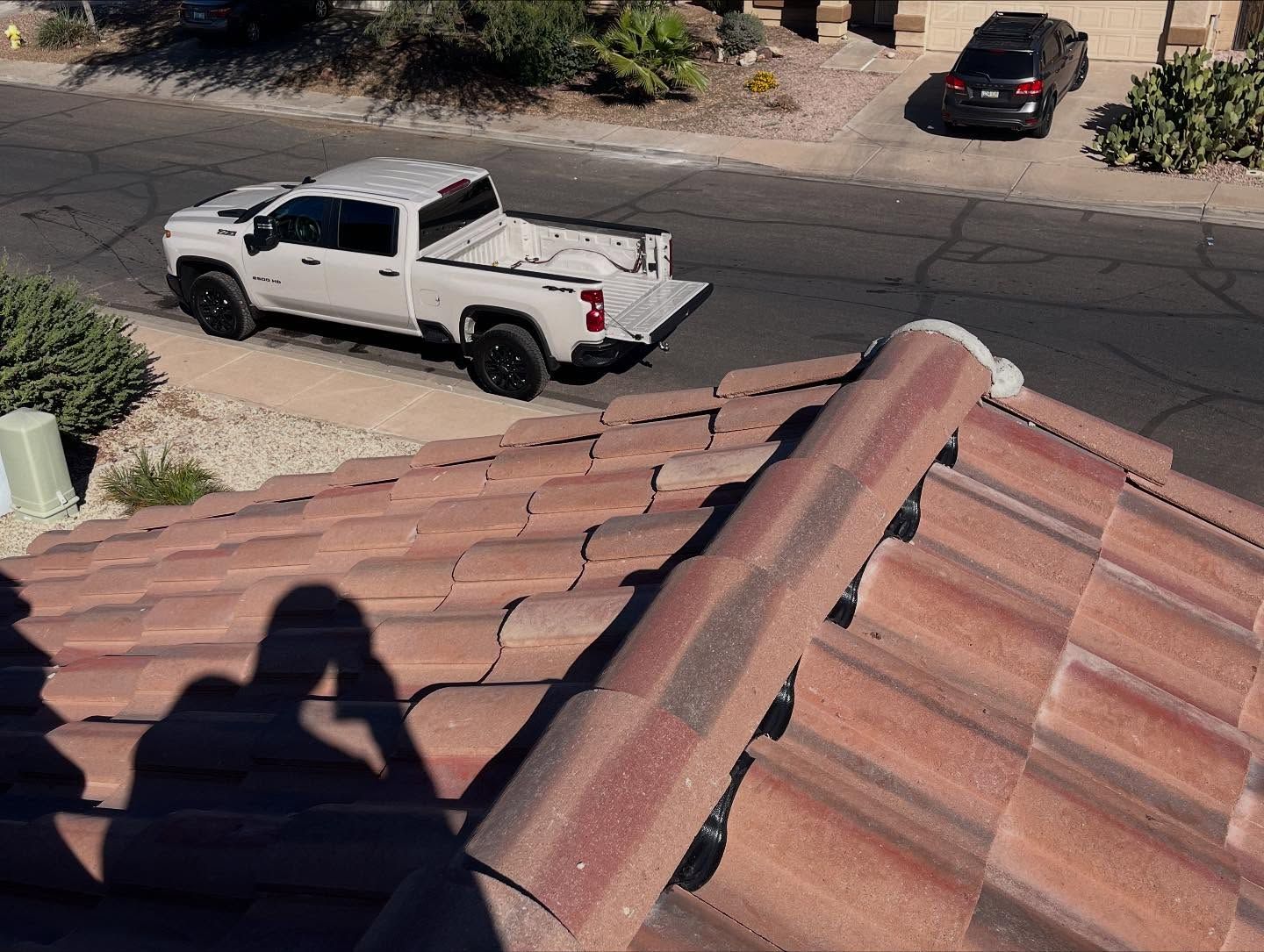 Shadow on red tile roof, white pickup truck on street, black SUV parked nearby.