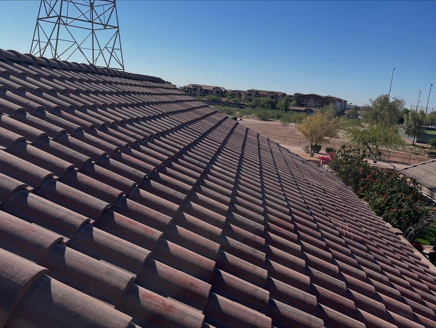 Brown tiled rooftop with a landscape view under a blue sky, power lines in background.