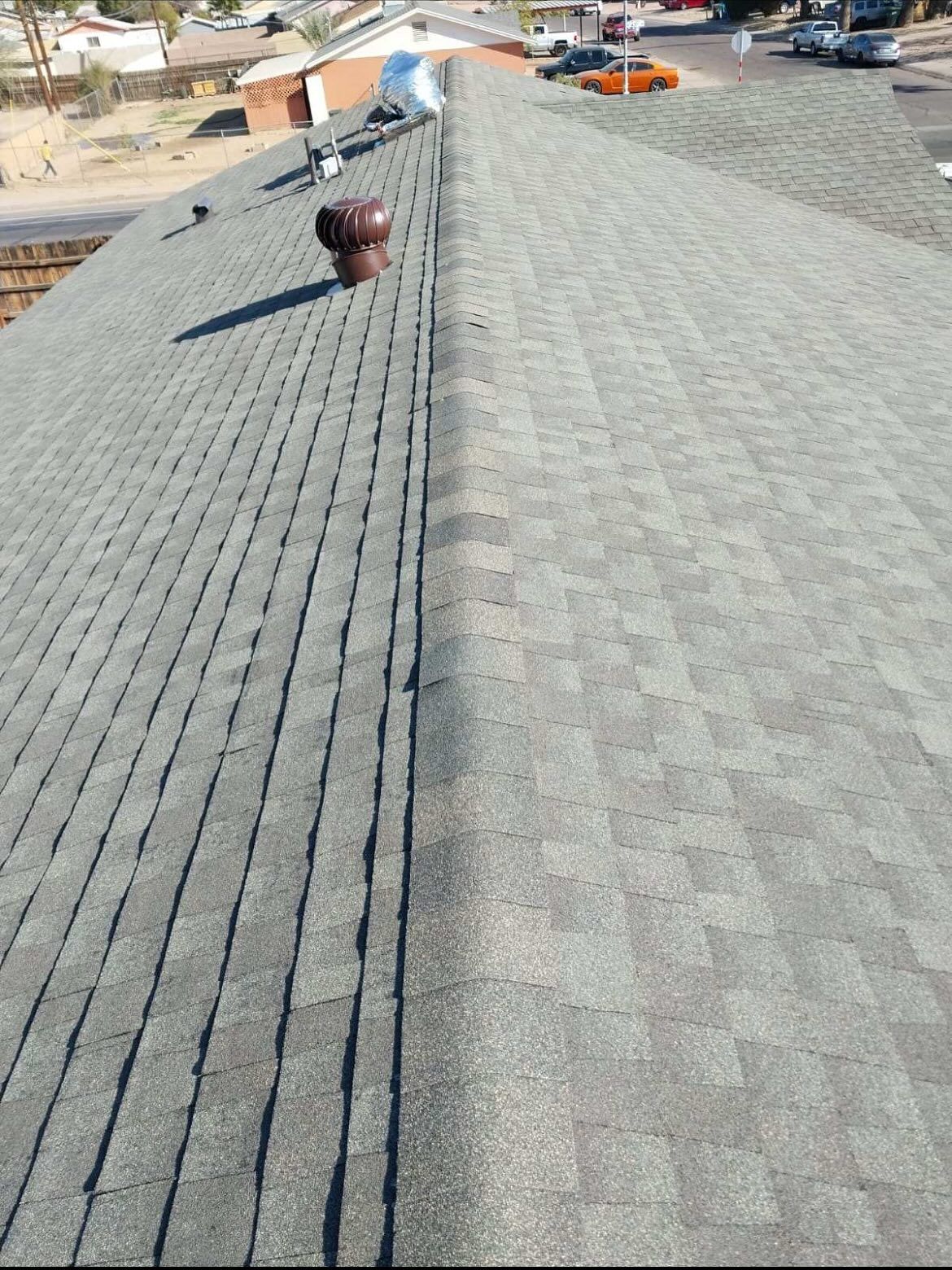 A rooftop with two sides, one dark gray and the other light gray, extending towards a street.