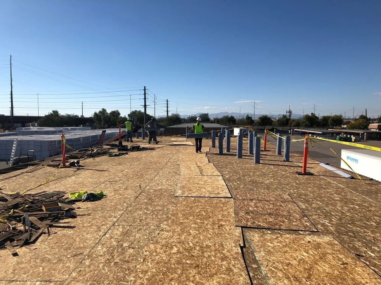 Construction site: Workers on a wooden platform, installing posts. Clear sky, sunny day.