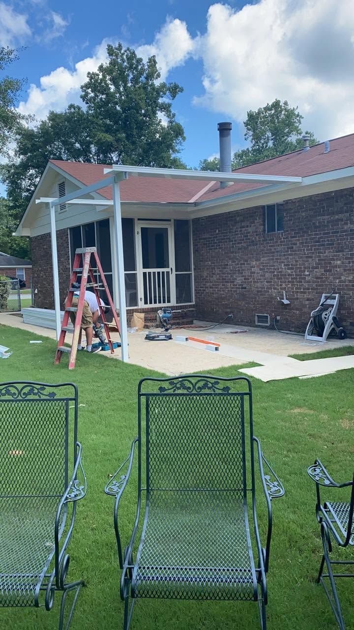 Backyard patio with brick house, ladder, patio chairs, and tools during outdoor work