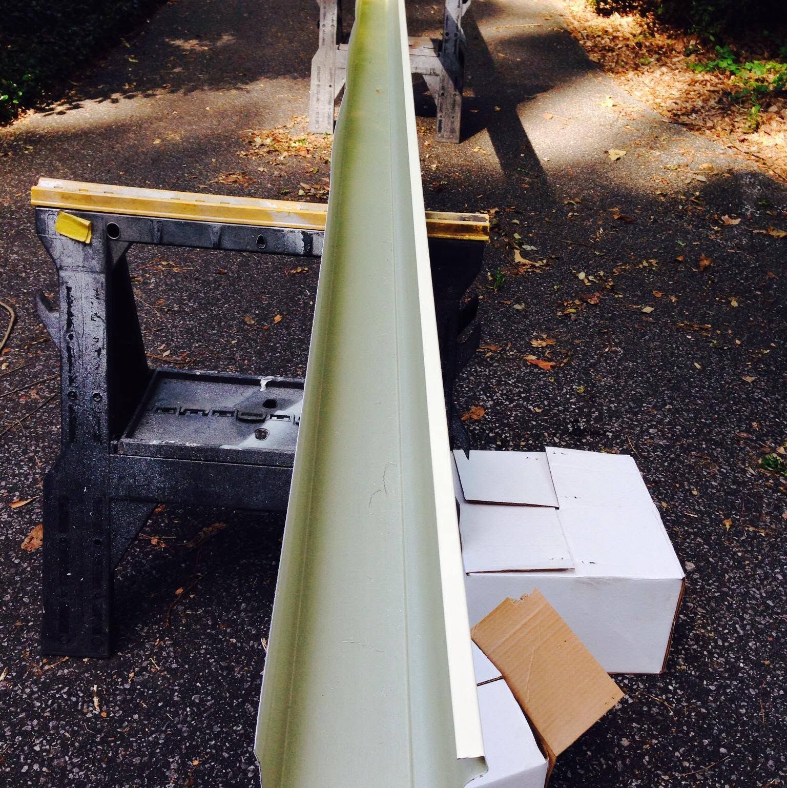 Long pale green beam balancing over black sawhorse and white boxes on a driveway