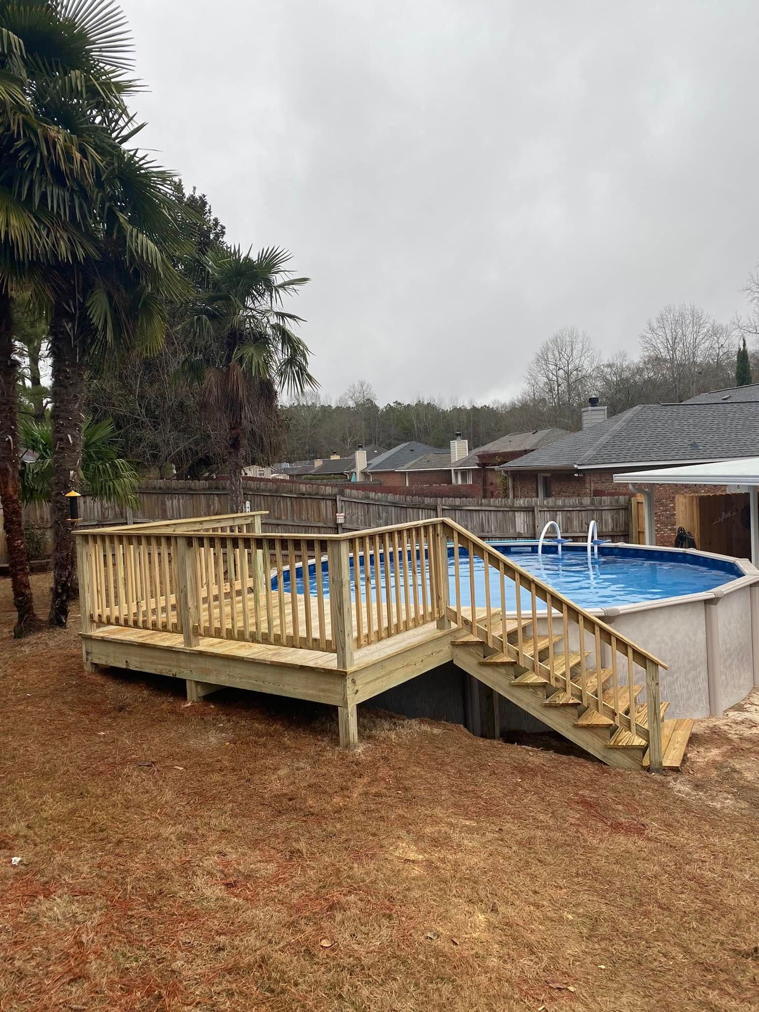 Wooden deck with stairs beside an empty above-ground pool in a backyard on a gray day