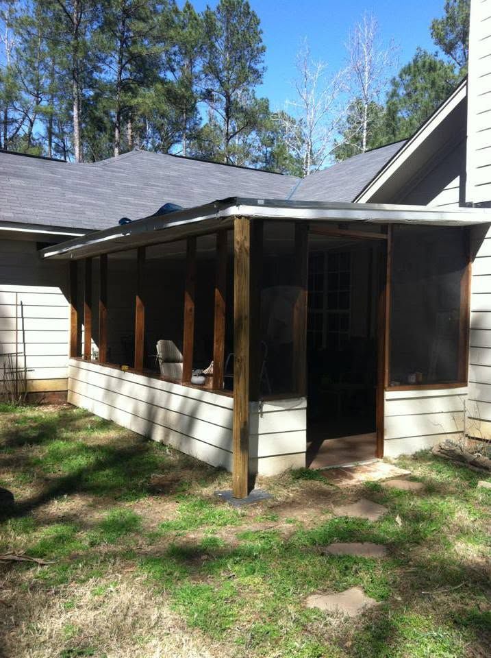 Screened porch on a beige house with white trim and a dark roof, surrounded by trees and grass.