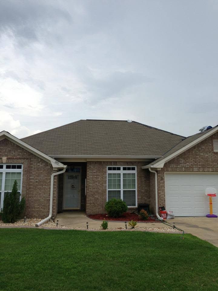 Single-story brick house with a front lawn, driveway, and a child’s bike near the garage.